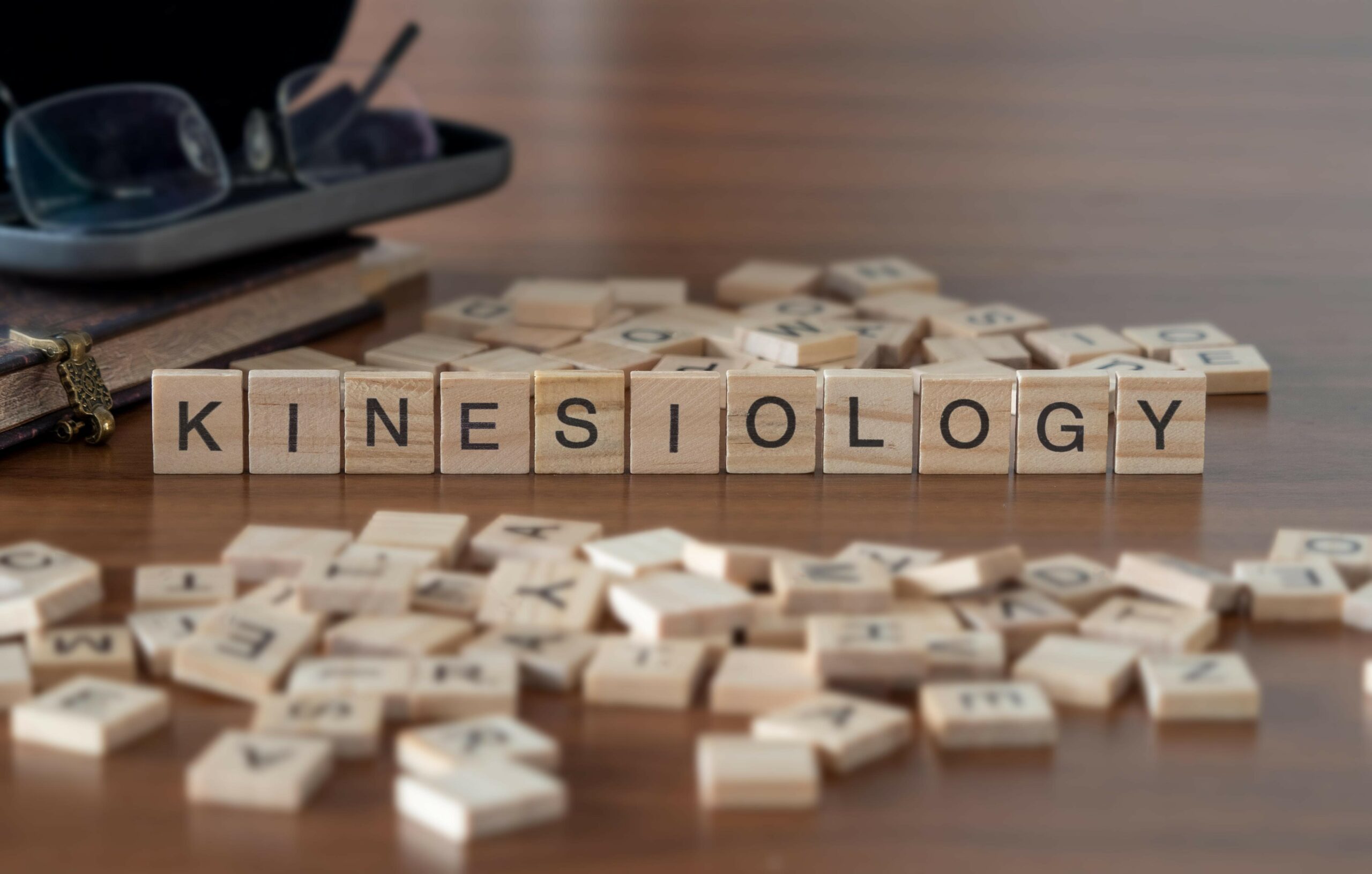 Lettres du jeu de Scrabble formant le mot KINESIOLOGY, une image éditoriale autour de la kinésiologie
